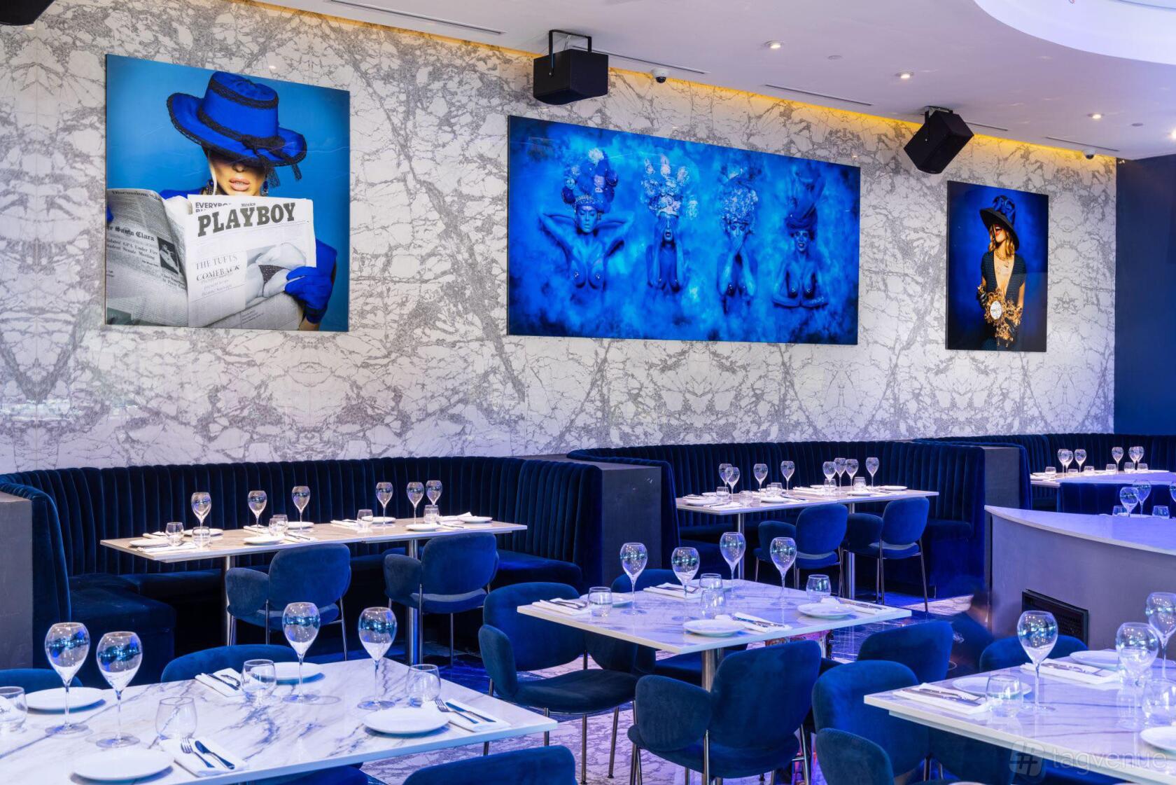 An event space with marble walls, blue velvet banquettes, and wall art at CIEL Restaurant & Lounge.