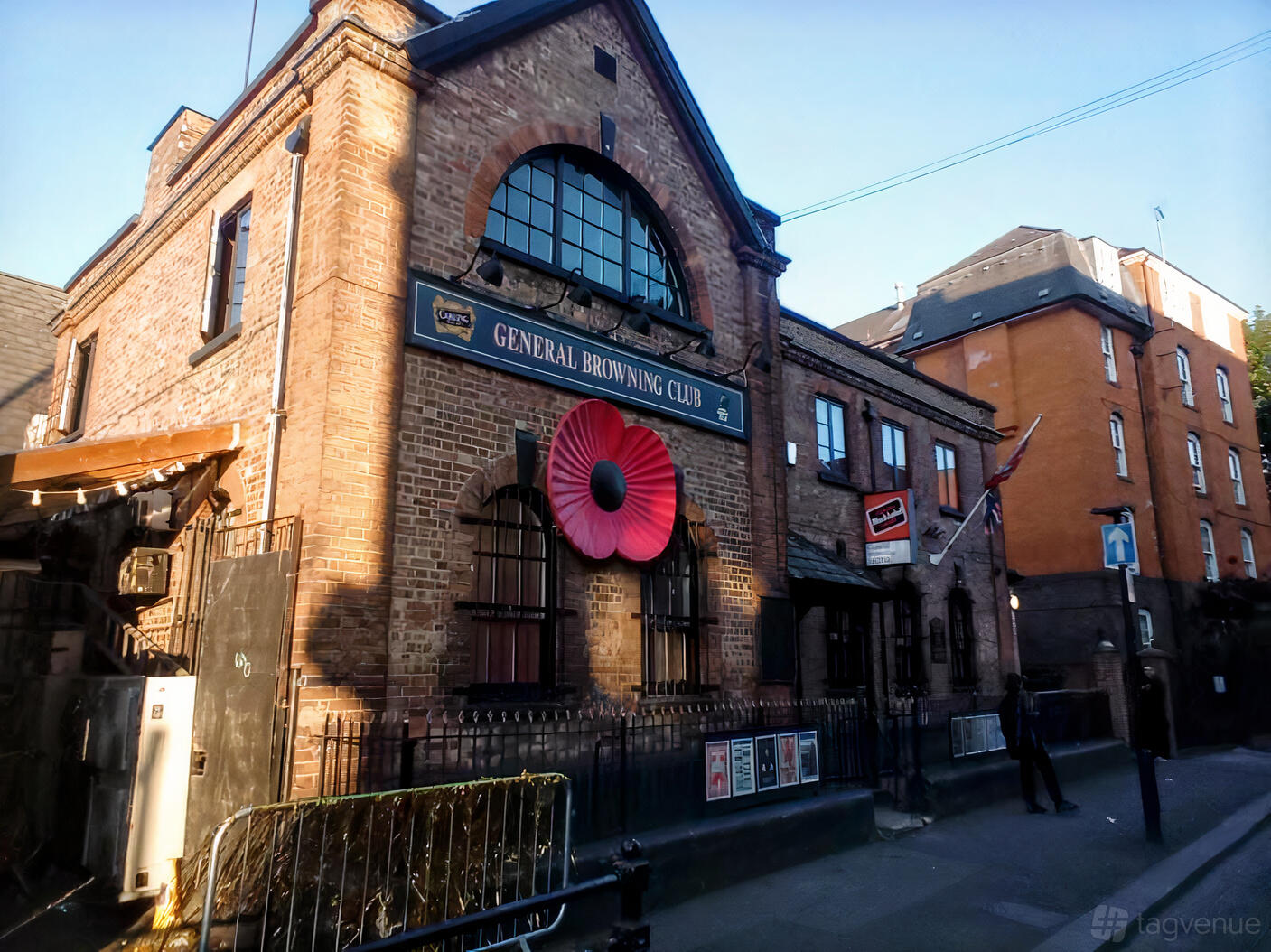 A brick pub with arched windows, black iron railings, and a large red poppy on the facade at MOTH Club.