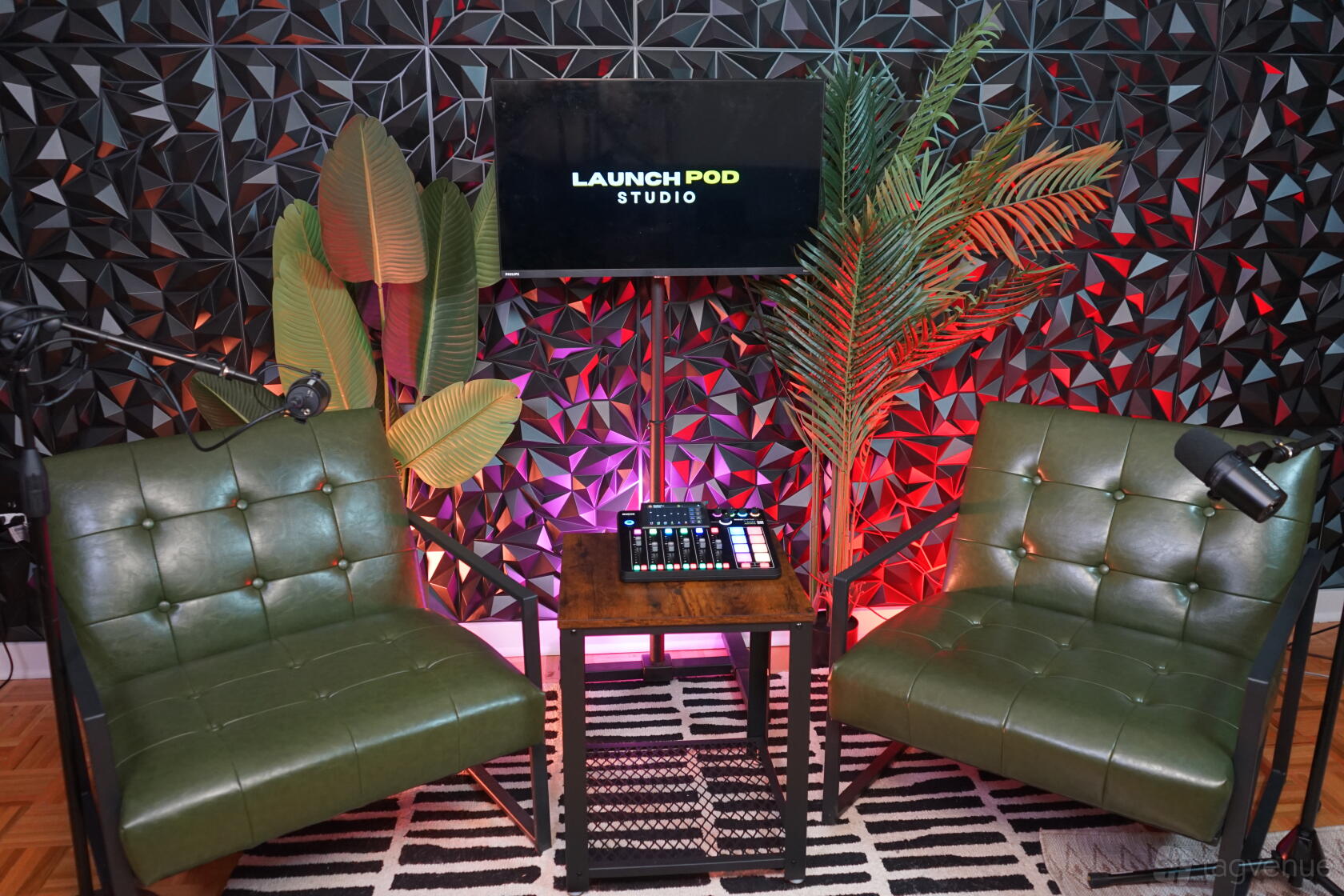 A podcast studio with two green armchairs, microphones, a sound mixer, and a patterned wall at Podcast Studio in Midtown Manhattan.