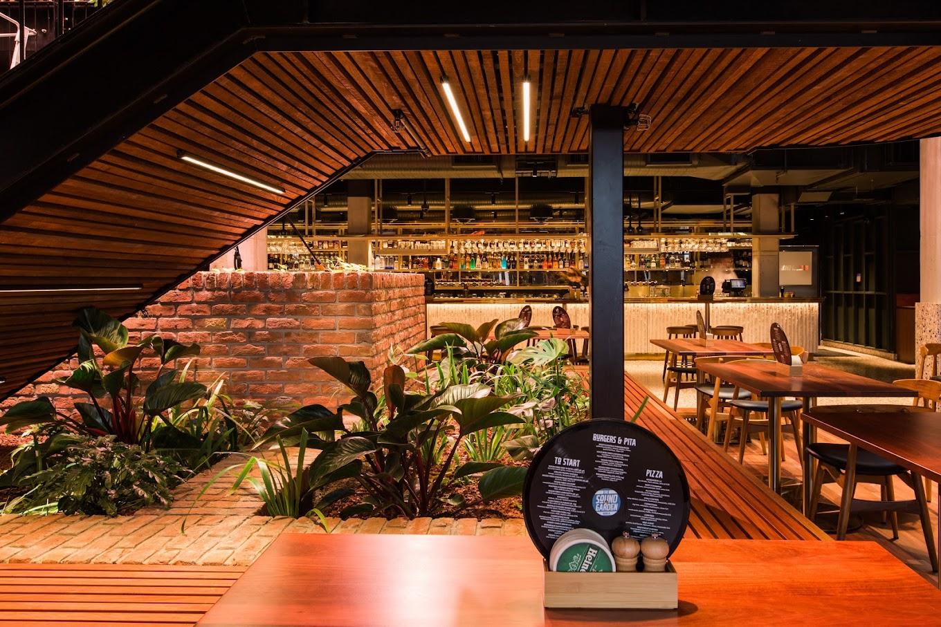 An event space with exposed brick planters, wood ceiling panels, and tables near a bar at The Sound Garden.