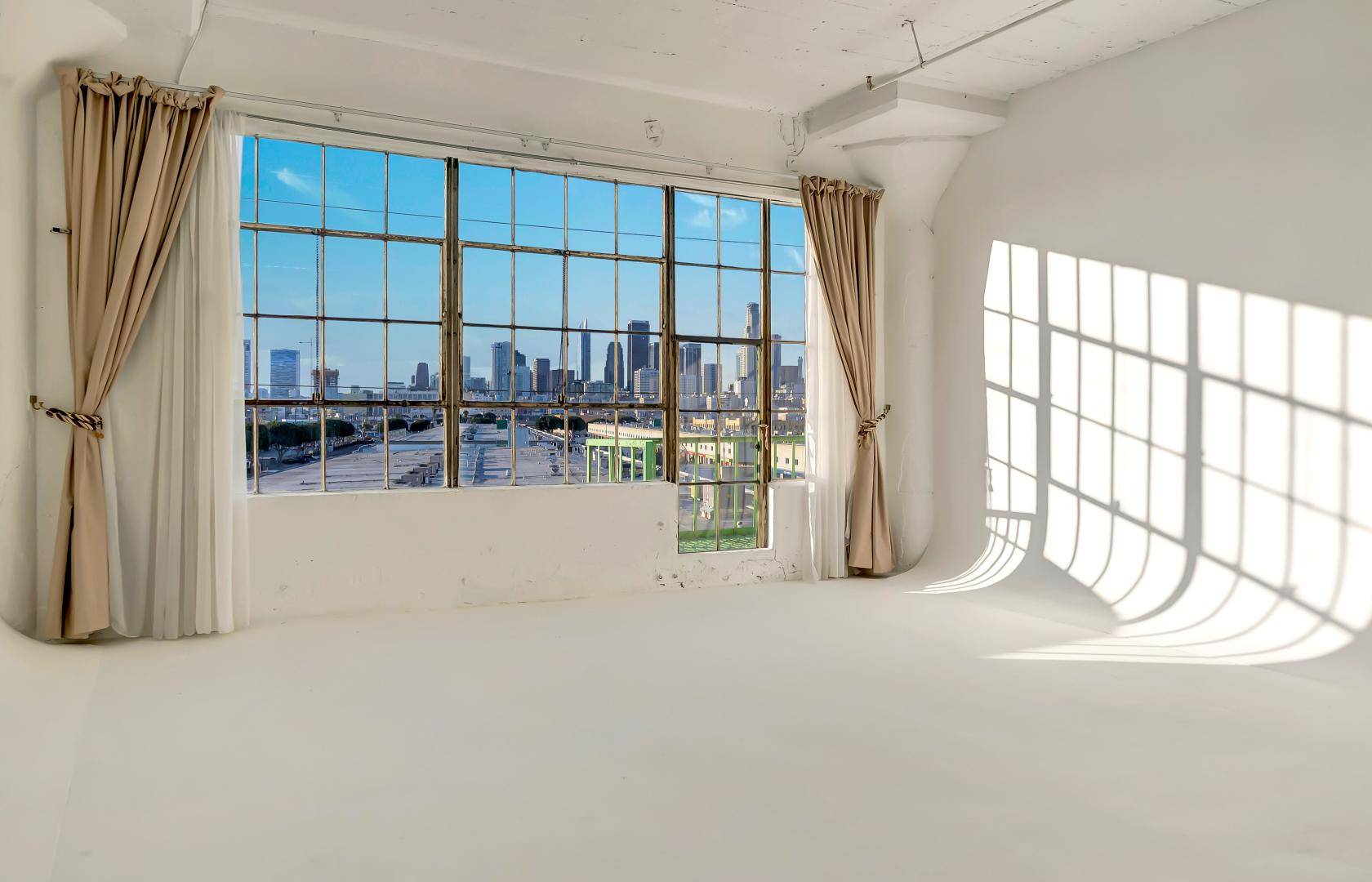 A photo studio in a warehouse with large industrial windows, white cyc wall, and natural light at Alameda Tower.