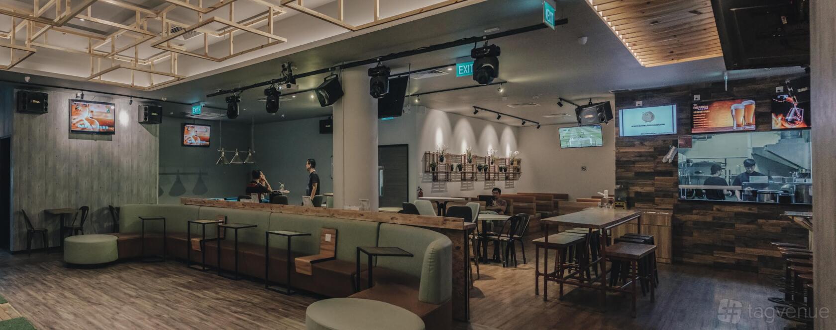 A hall in a bar with booth seating, wooden tables, TV screens, and overhead stage lights at 7th Heaven KTV Cafe.