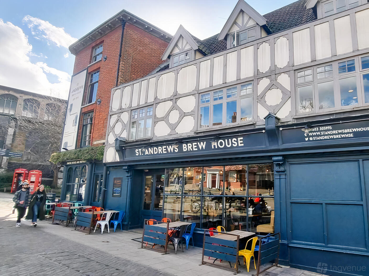 A pub with outdoor seating, colorful chairs, and a timber-framed facade at St Andrews Brewhouse.