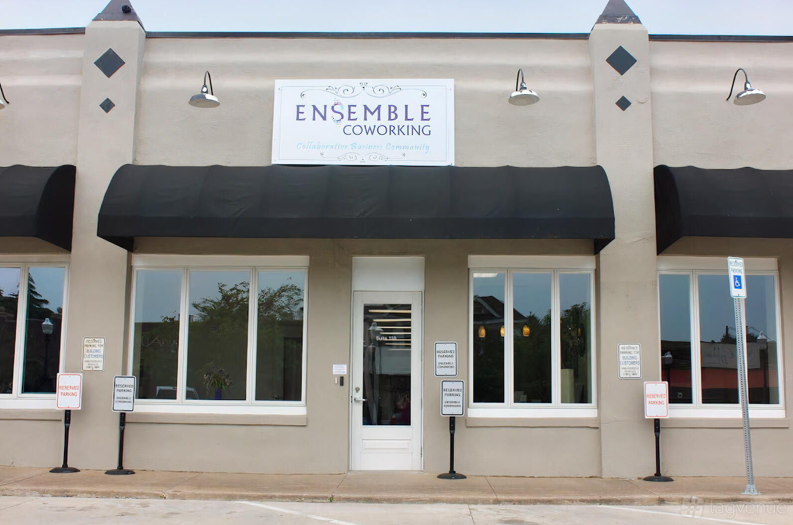 A meeting centre with a light-colored facade, large front windows, and black awnings at Ensemble Coworking.