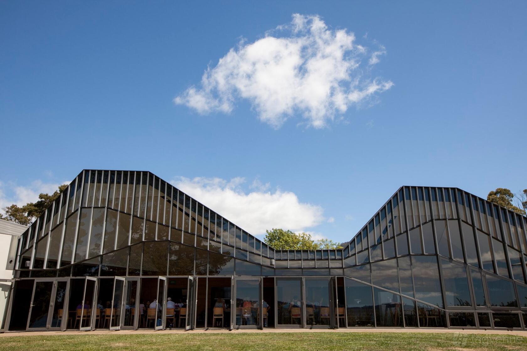 A hotel with angular glass exterior walls and lawn under a blue sky at Peppermint Bay Hotel