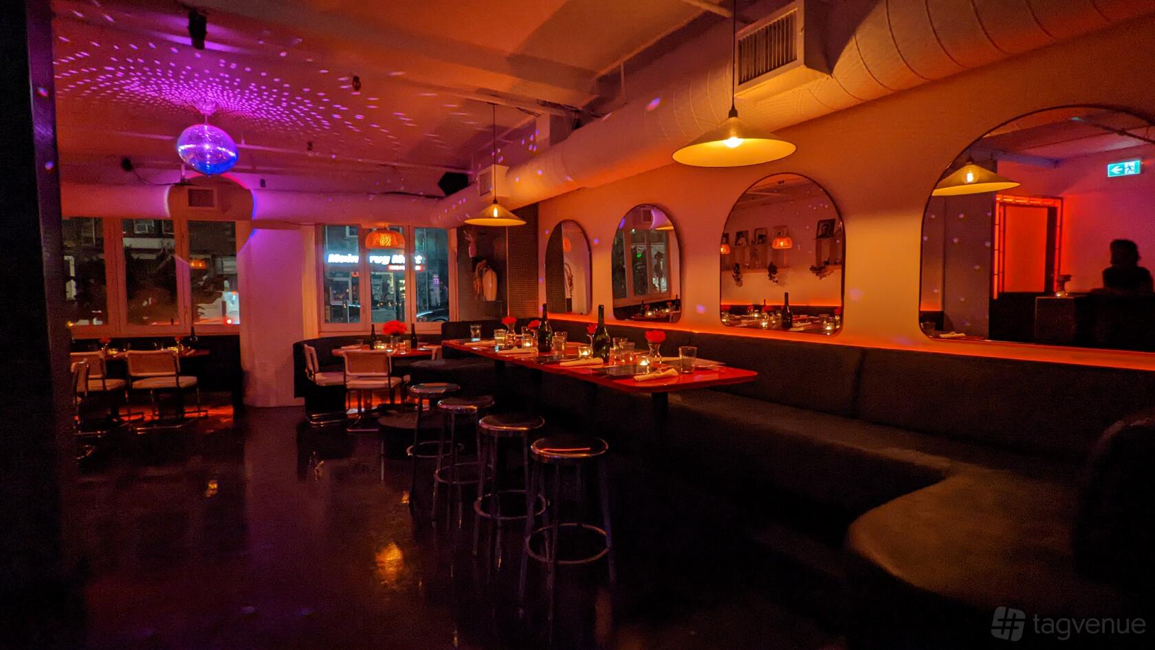 A restaurant with a disco ball, ambient lighting, and long banquette seating at Sprezzatura Spaghetti Disco.
