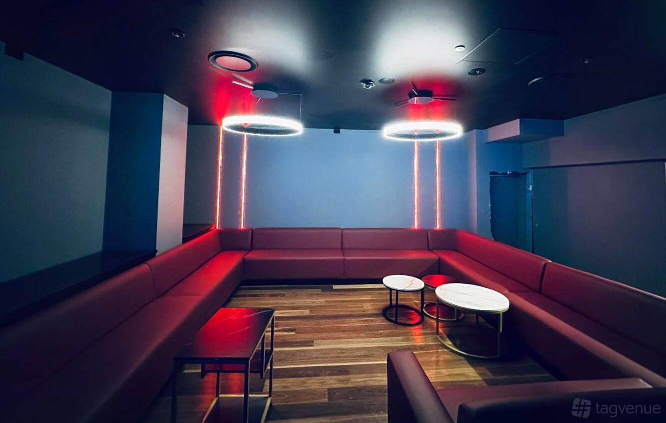 A restaurant lounge with red banquette seating, round marble tables, and ring pendant lights at The Maya Lounge Sydney.