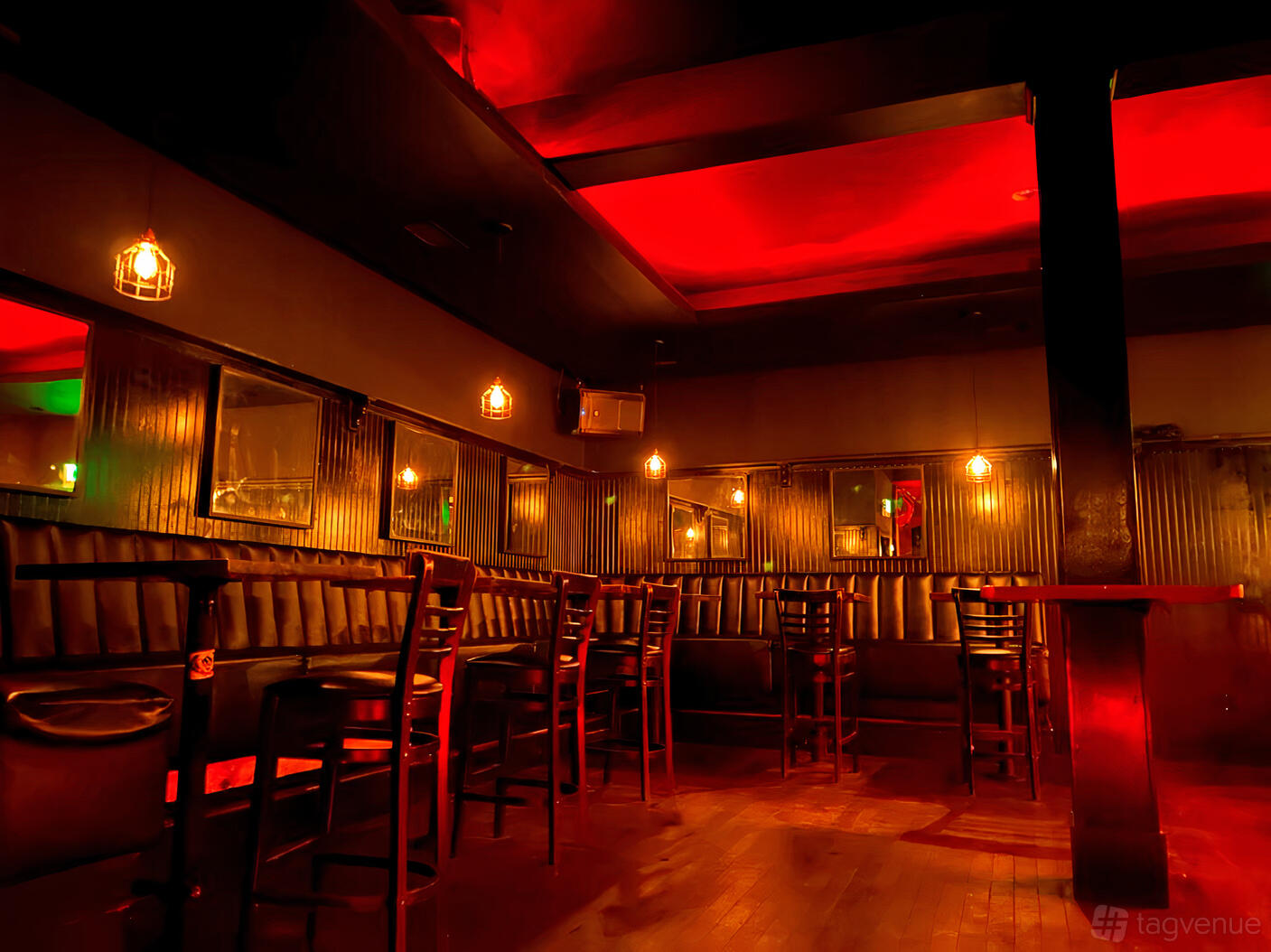 A bar with red lighting, hanging pendant lights, black booths, and high-top tables at Knucklehead.
