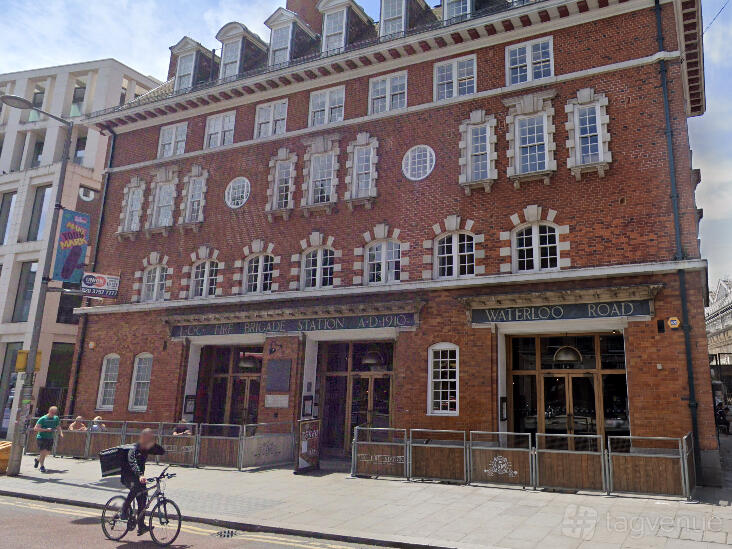 A pub in a historic red brick building with arched windows and outdoor seating at The Fire Station.