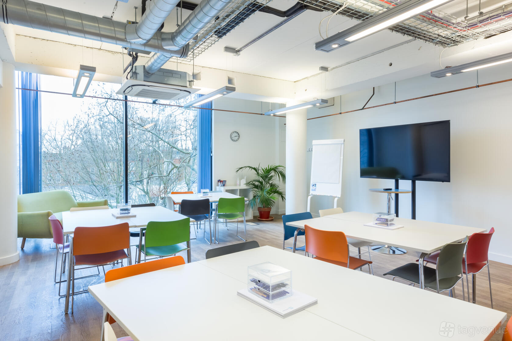 A training room with colorful chairs, large windows, and a presentation screen at Wallacespace Clerkenwell Green.