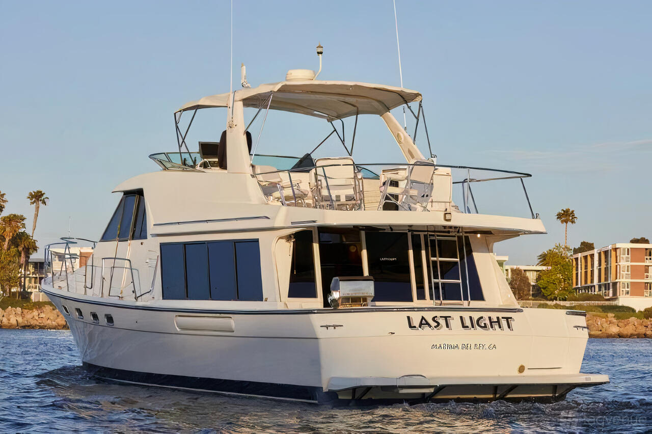 A yacht with an upper deck, shaded seating area, and waterfront views at Luxury Yacht Charter.