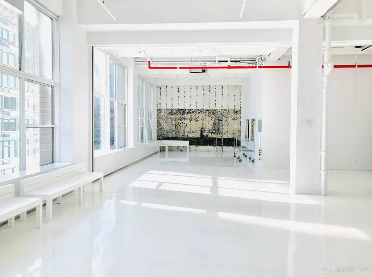 An event venue with white glossy floors, large windows, and a distressed accent wall at Location 05.