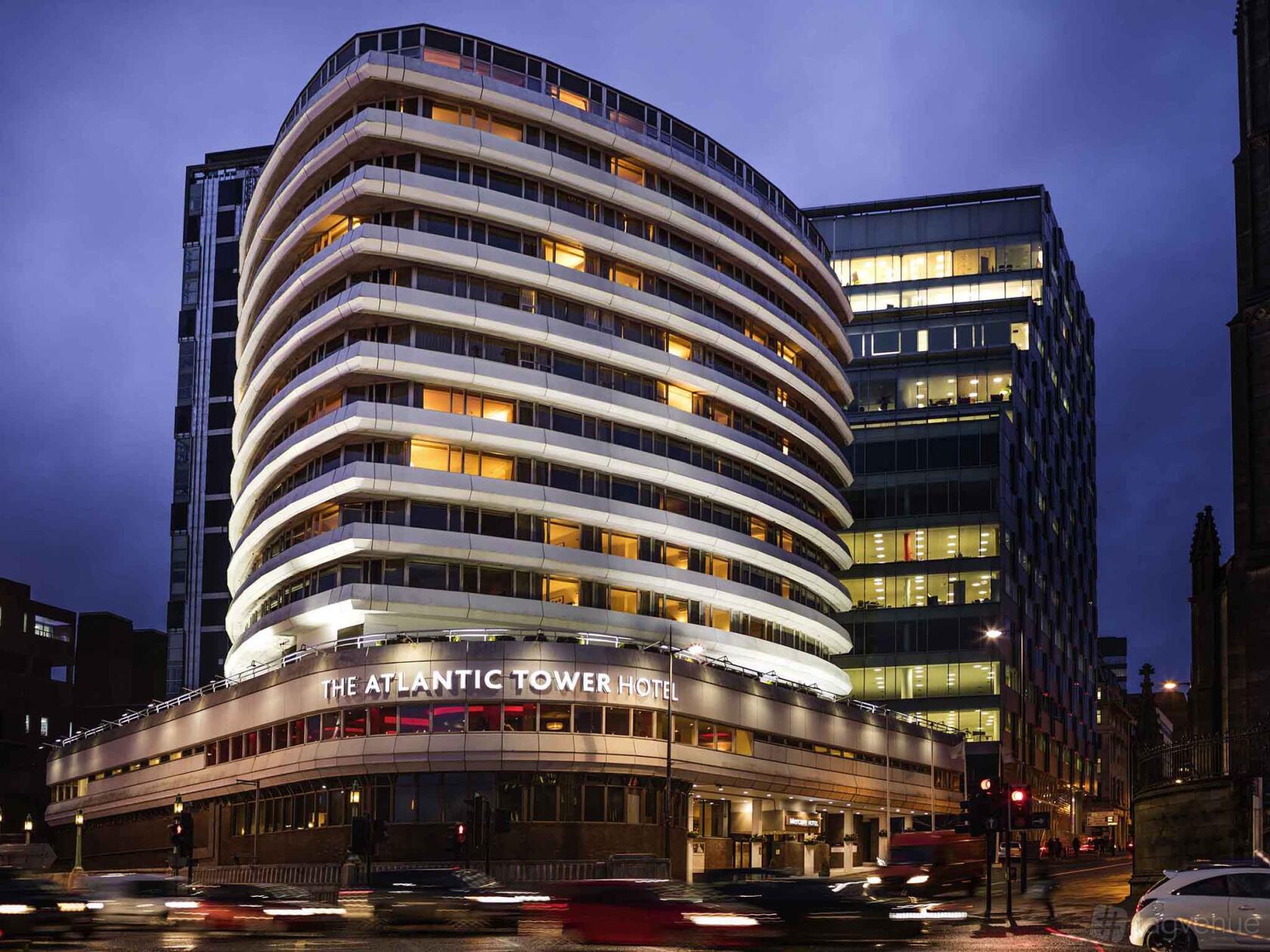 A hotel with a curved white facade, large balconies, and illuminated exterior at Atlantic Tower Hotel Liverpool By Sunday.
