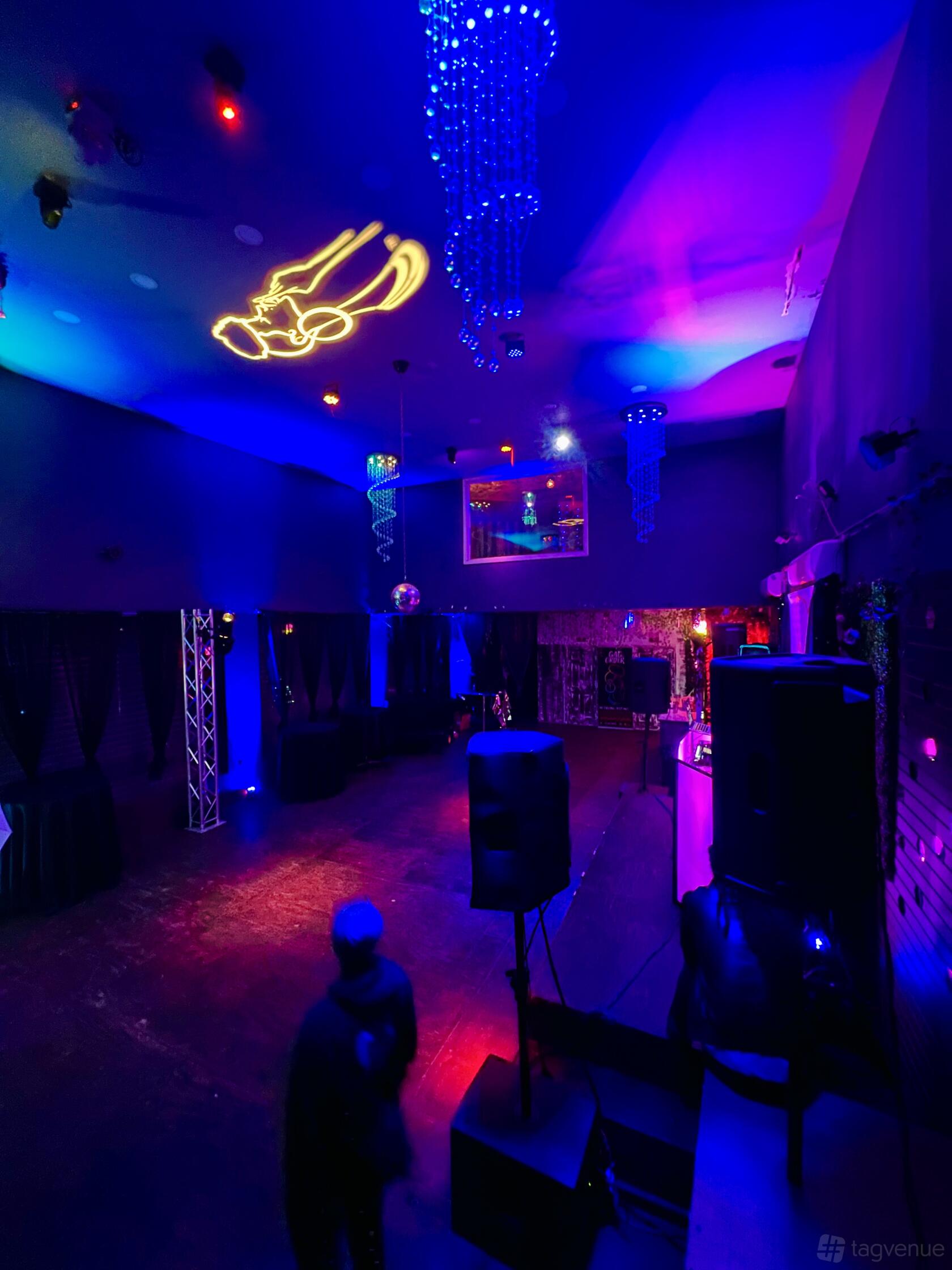 A hall with vibrant colored LED lighting, mirrored walls, and a DJ booth at Brooklyn Burj.