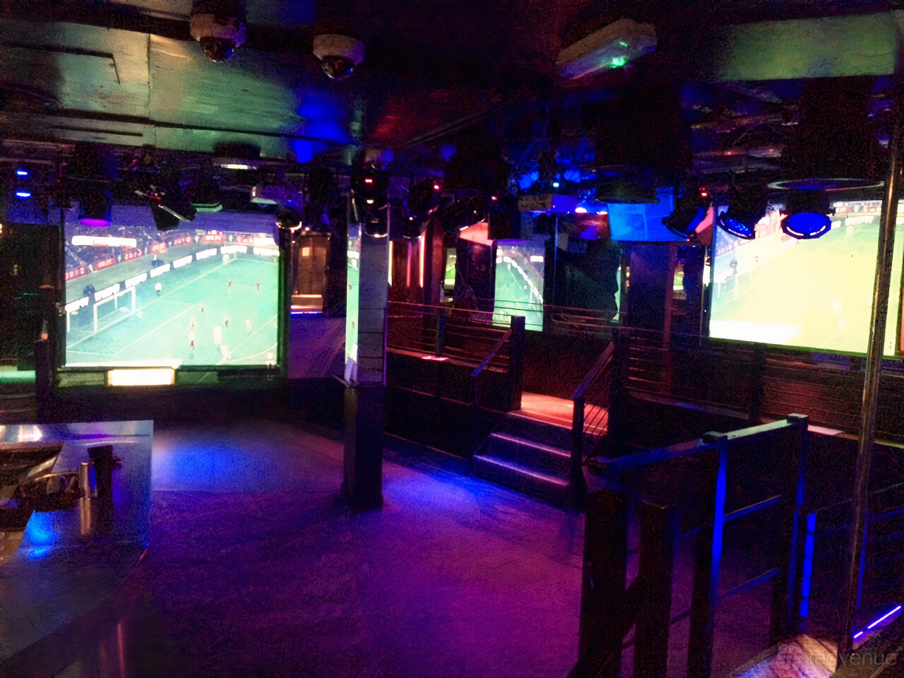 An event space in a nightclub with large projection screens, colorful lighting, and tiered seating at Zoo Bar.