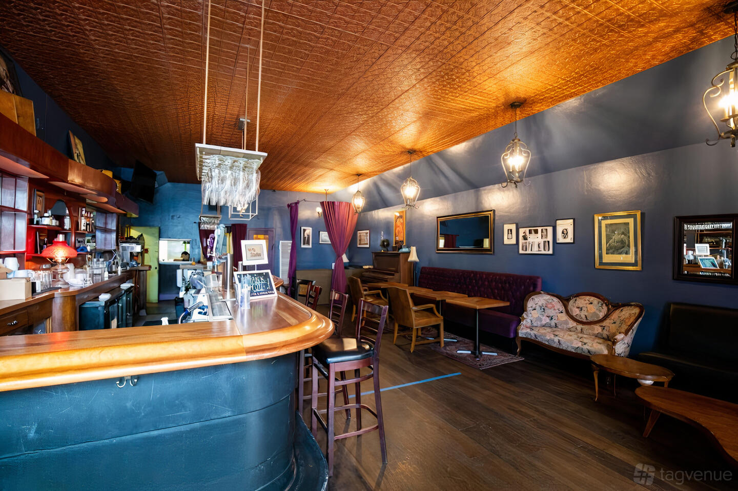 A restaurant with a wood-paneled ceiling, vintage sofas, a long wooden bar, and framed art at Gentilly.