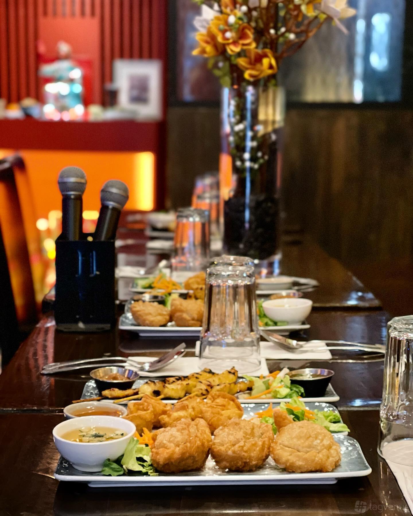 An event space in a restaurant with banquet seating, tabletop microphones, and Thai appetizers at Udom Thai.