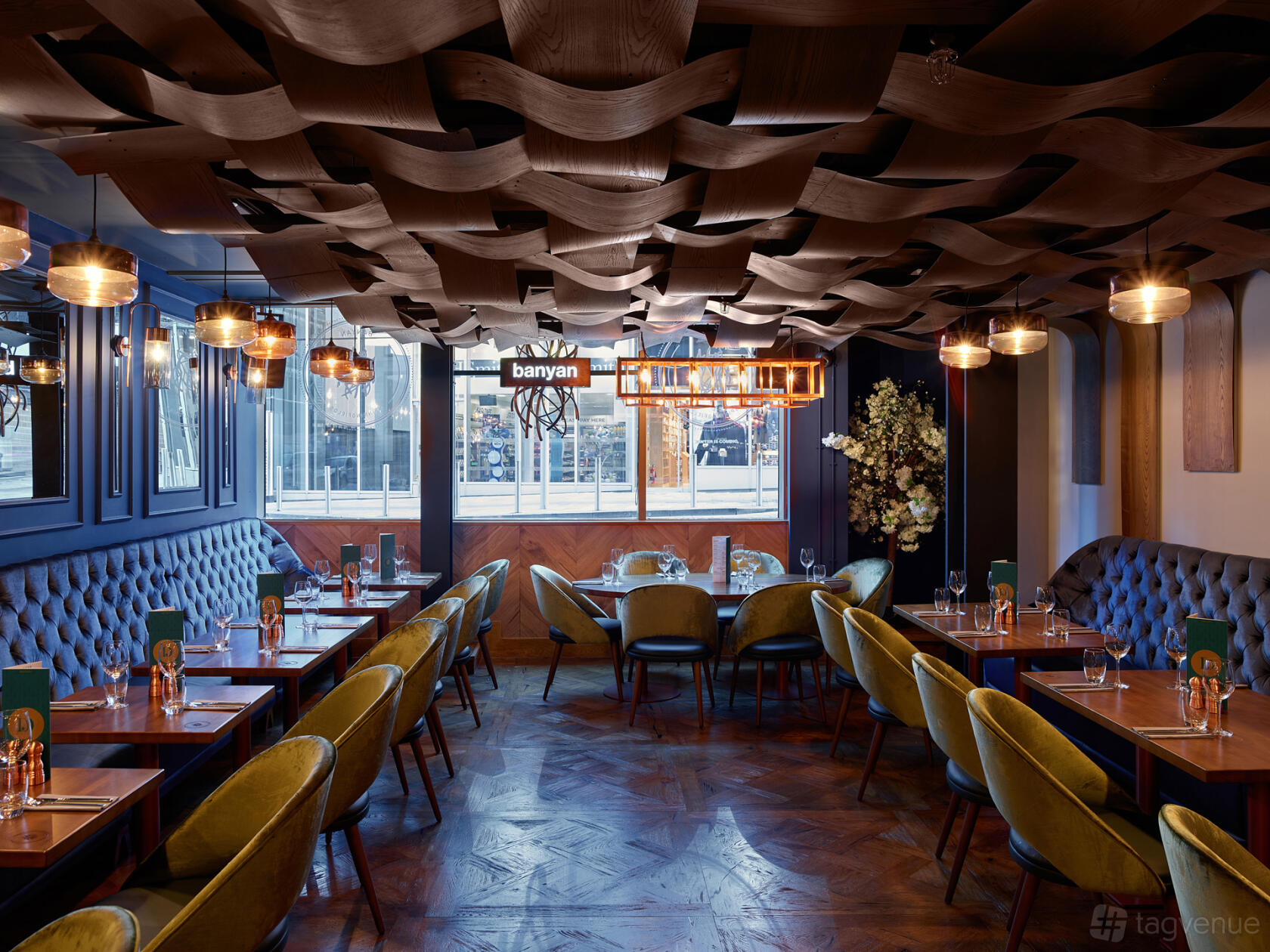 An event space with patterned ceiling, velvet chairs, and floor-to-ceiling windows at Banyan Spinningfields.