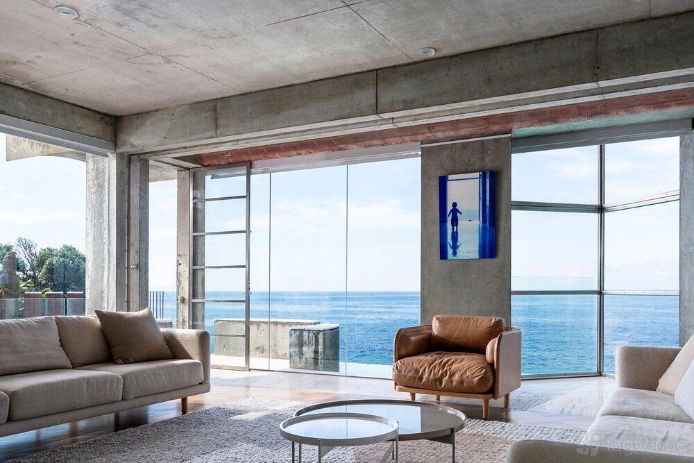 An event space in a castle with floor-to-ceiling windows, ocean views, and modern seating at Crypto Castle - Photography/filming Location.