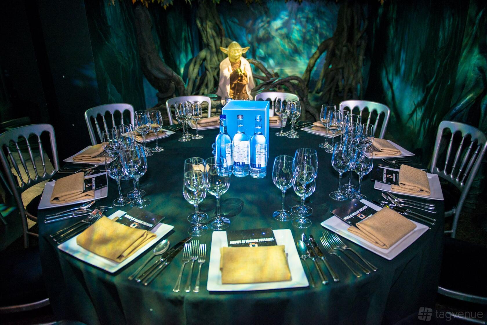 An event space in a museum with a round table set for dinner near a Yoda figure at Madame Tussauds.