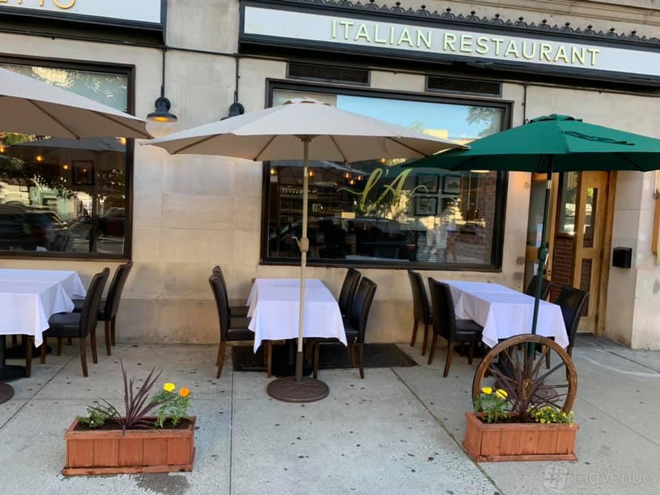 A restaurant terrace with outdoor seating, white tablecloths, and large umbrellas at L'Angeletto.