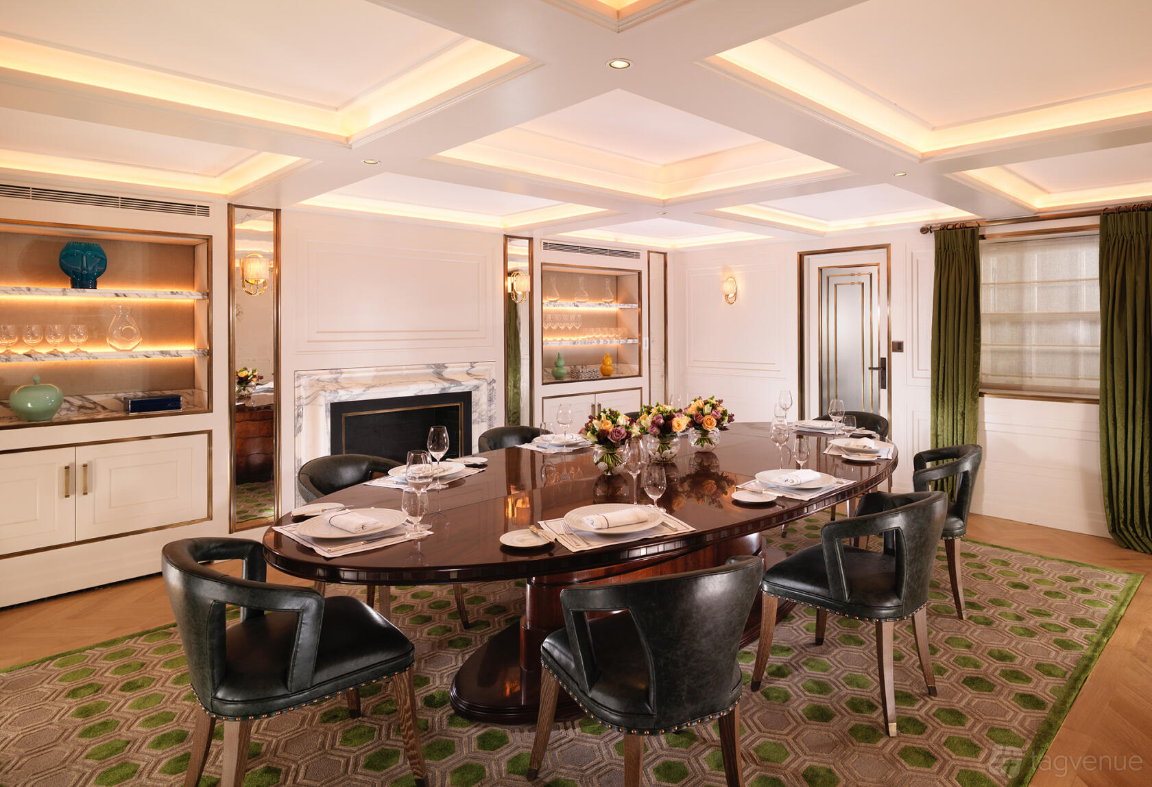 A hotel private room with a polished oval dining table, black chairs, fireplace, and built-in display cabinets at Flemings Mayfair.