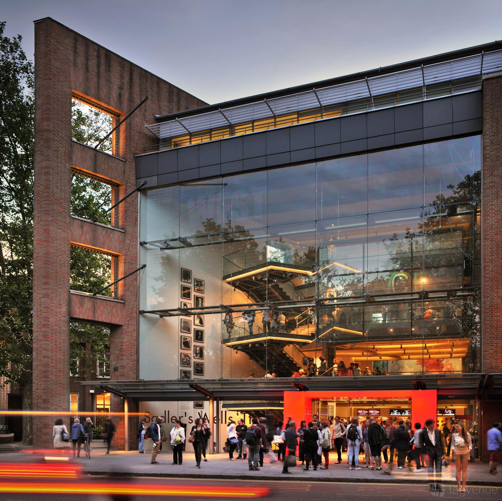 A theatre with a glass-fronted facade, visible staircases, and red brick exterior at Sadler's Wells.