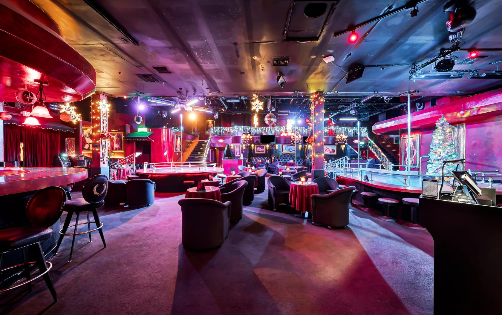 A nightclub with round tables, plush chairs, a stage, string lights, and festive decorations at Club Featured in HBO's Euphoria.