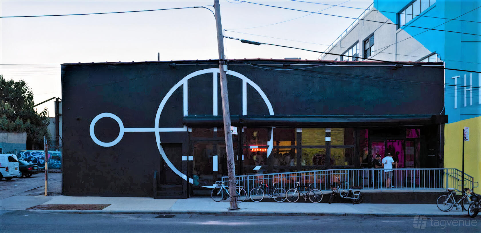 A warehouse venue with industrial exterior, large geometric mural, and outdoor bike rack at Wandering Barman.