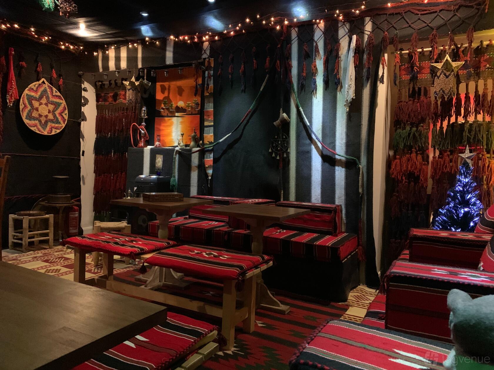 An event space in a restaurant with patterned textiles, woven wall hangings, and cushioned bench seating at Mora Meza Bar & Restaurant.