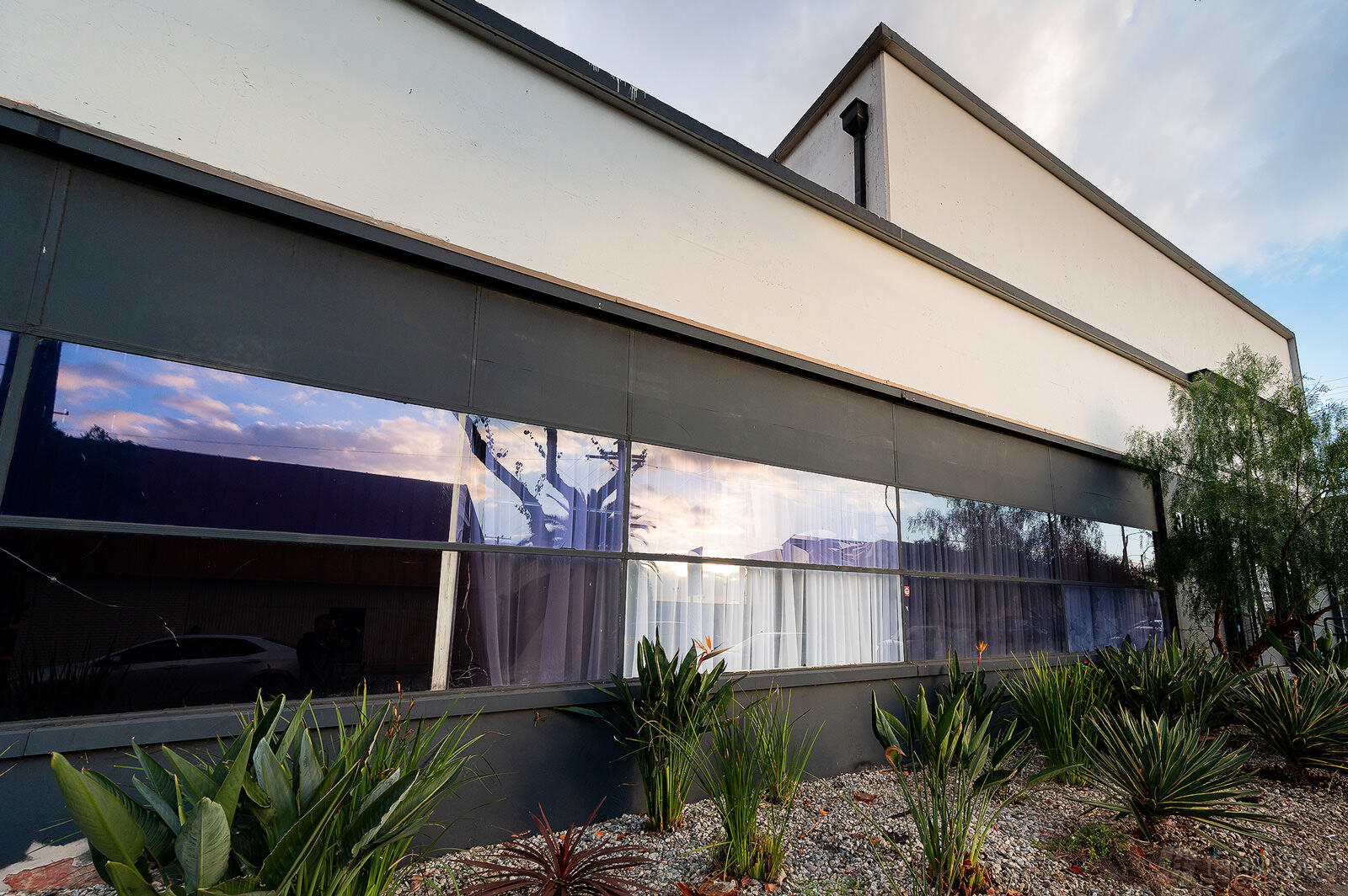 A film and photo studio with large reflective windows and desert landscaping at HI Studios LA.