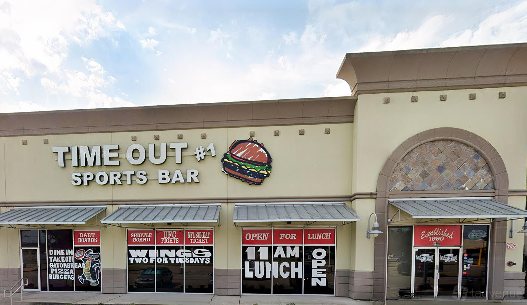 A pub and sports bar with a large burger sign, promotional window decals, and awnings at Timeout #1.