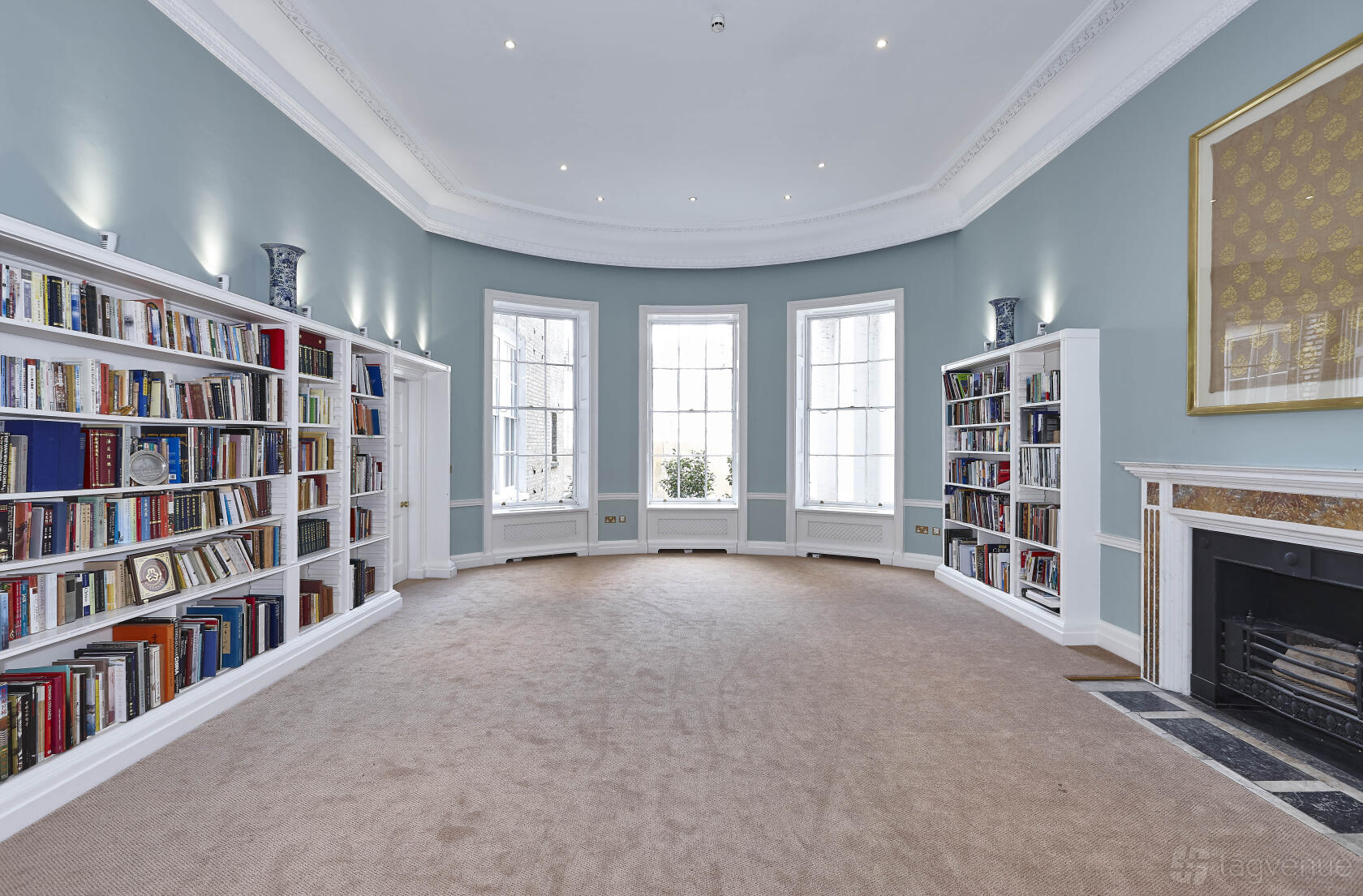 A dining room with built-in bookshelves, large bay windows, and a decorative fireplace at Asia House.