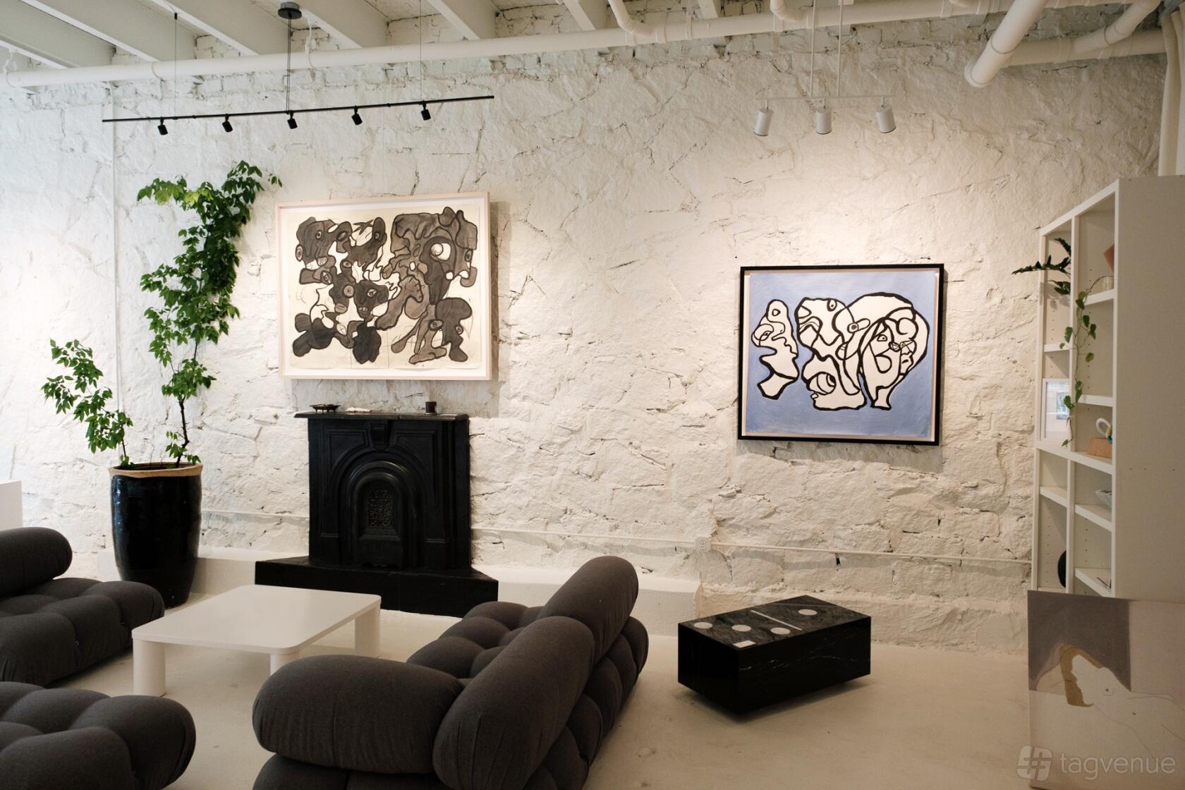 An art gallery event space with white textured walls, abstract paintings, and modern gray lounge seating at Memento.