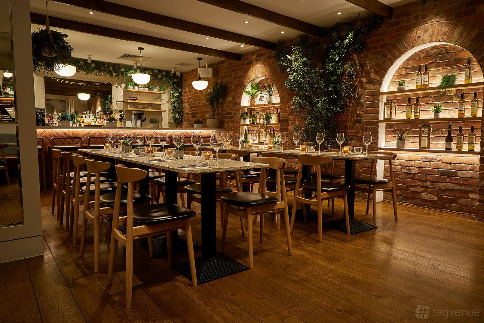 An event space in a restaurant with exposed brick arches, wooden tables, and greenery at Sunday in Brooklyn Notting Hill.