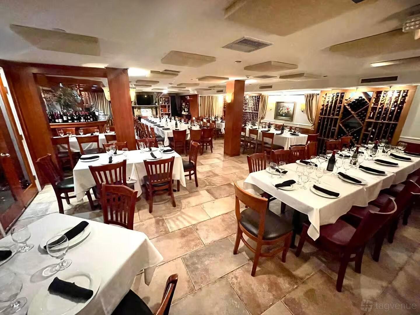 An event space in a restaurant with white tablecloths, wooden chairs, and wine racks at Lenny's Steakhouse.