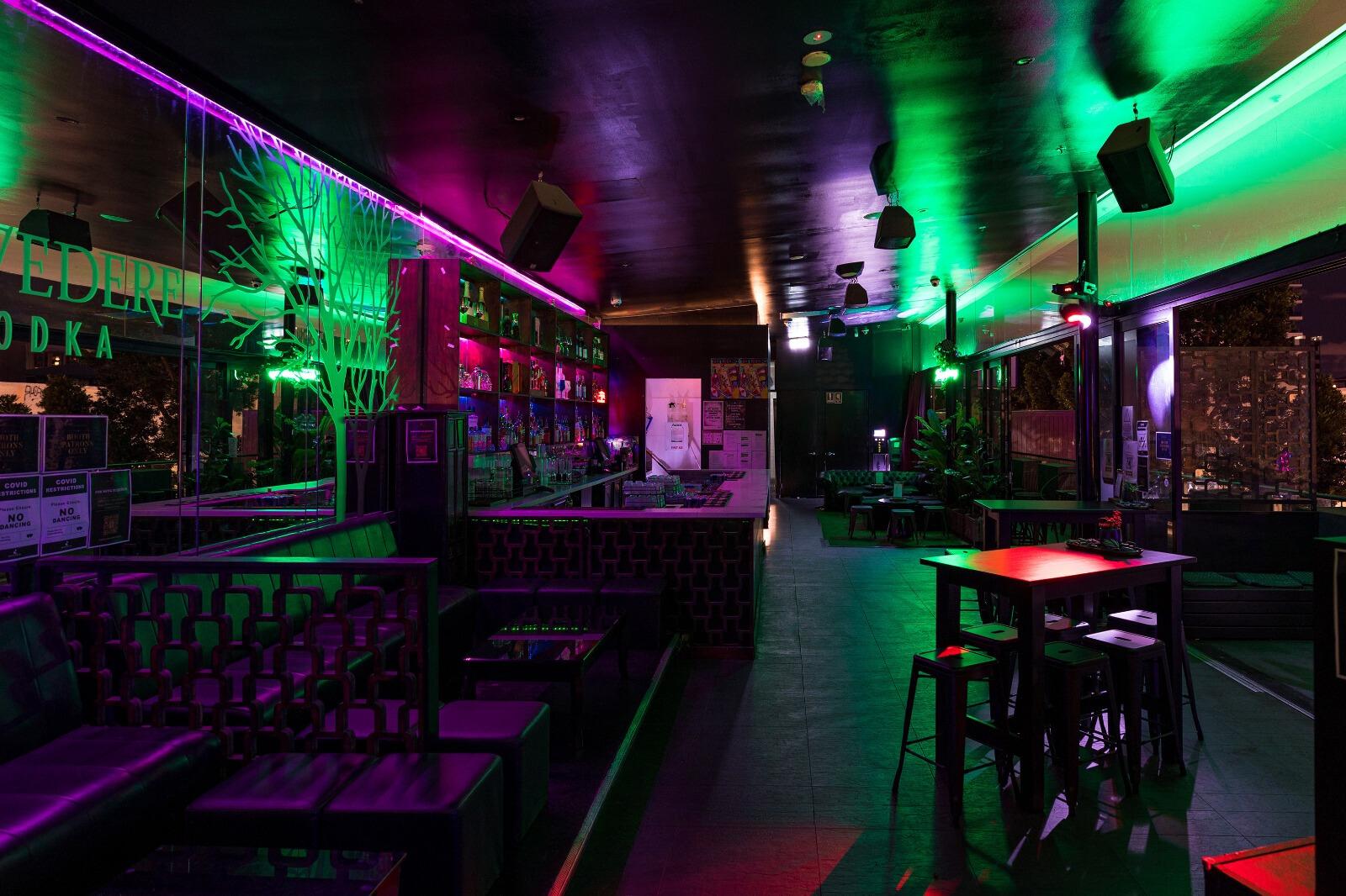 A dance studio with neon lighting, bar seating, and large windows overlooking the city at Sky and Lotus.
