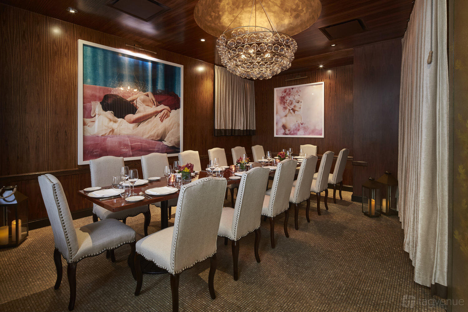 An event room with a long dining table, upholstered chairs, chandelier lighting, and large framed art at Fiola.