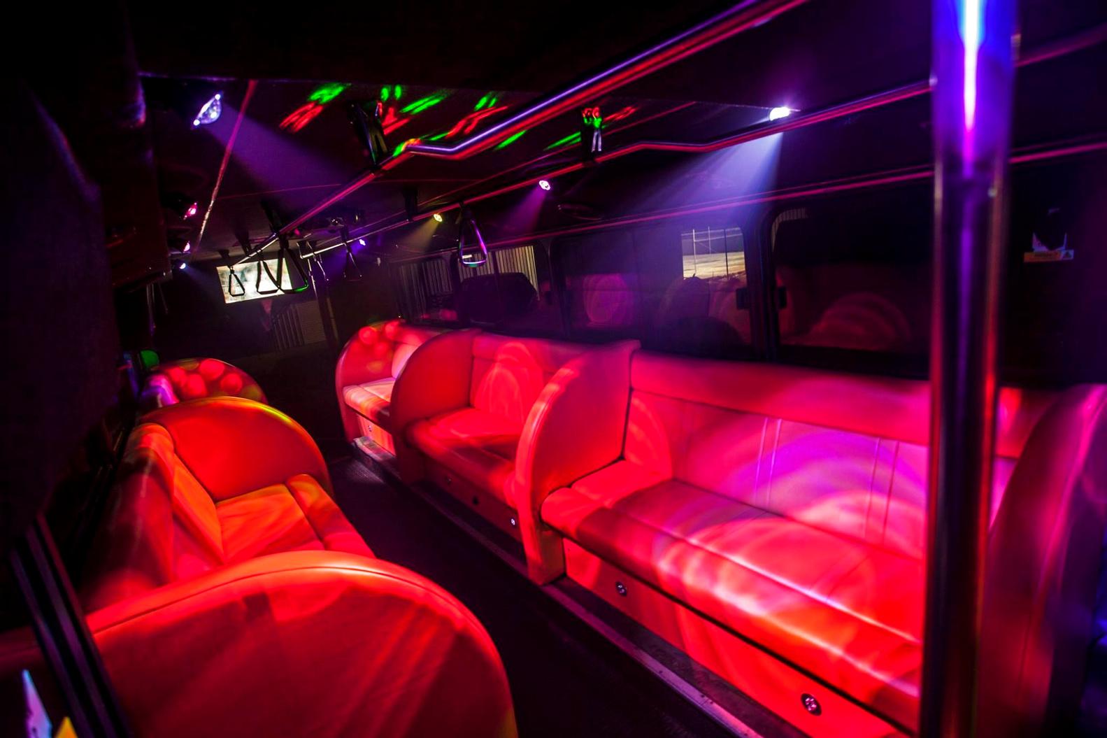 A party bus with red leather seating, colorful LED lighting, and a built-in sound system at DoubleUP Tours.