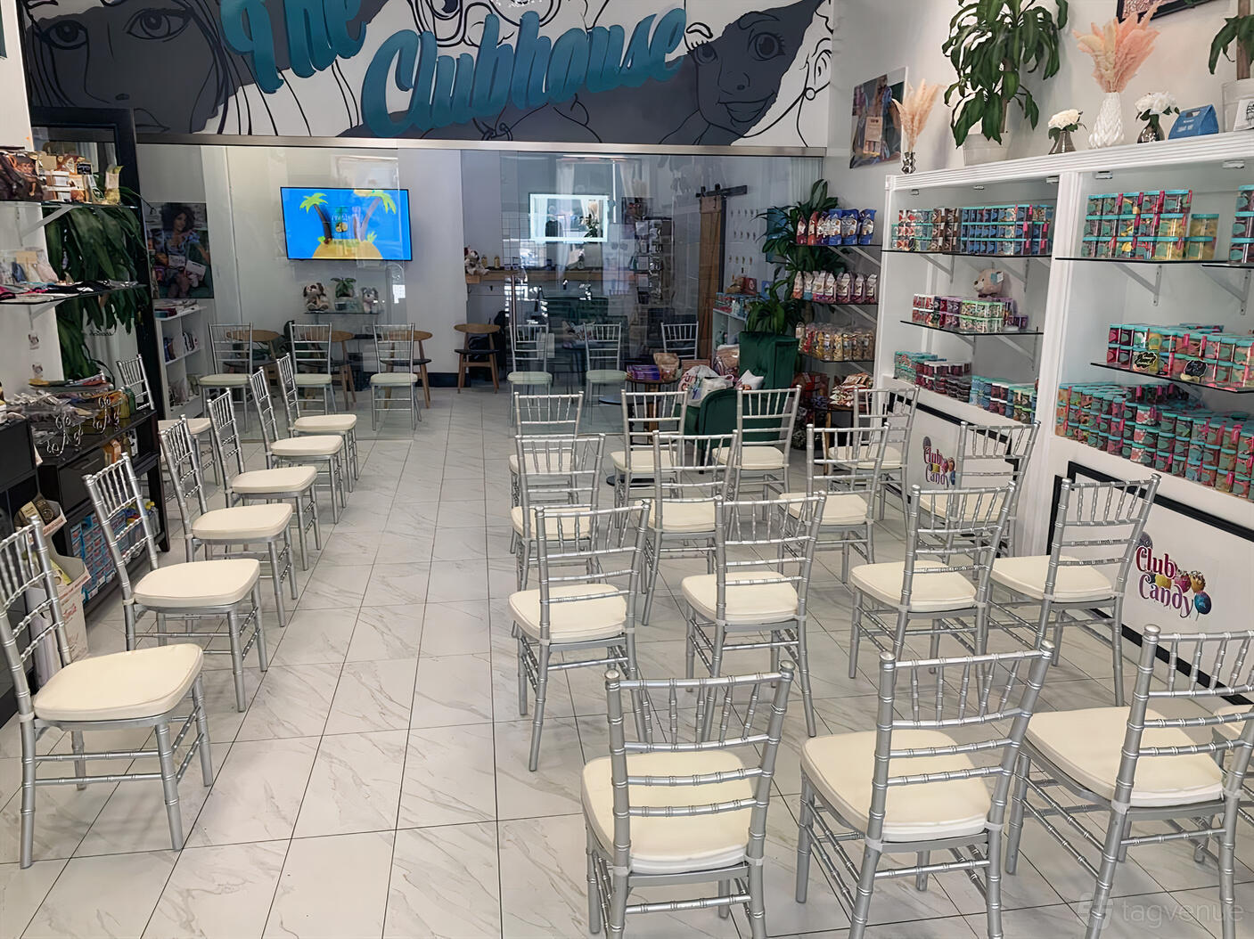 An event venue with white tile floors, silver chairs in rows, and colorful candy displays at Club Candy ATL.