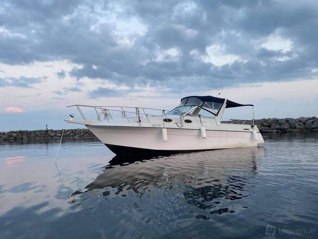 A motor yacht with open deck seating, navy canopy, and dockside views at Boats For The Boatless.