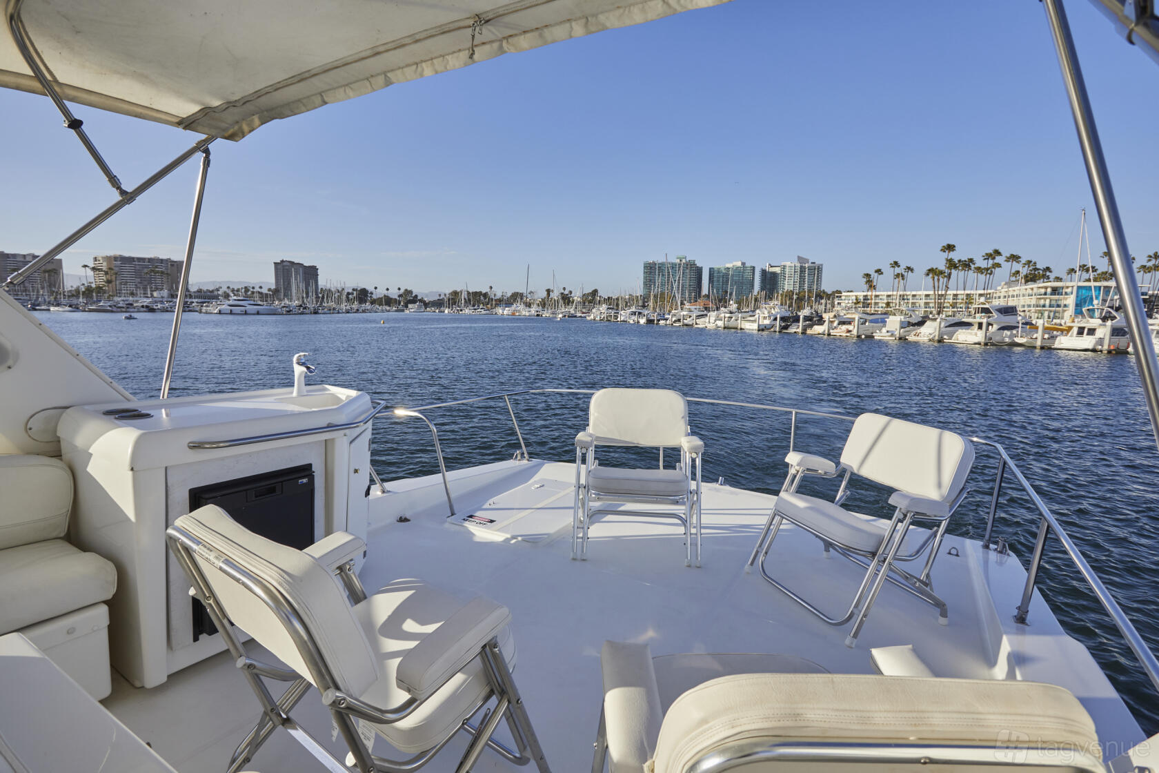A charter boat deck with white chairs, small bar area, and marina views at Parties at Sea.
