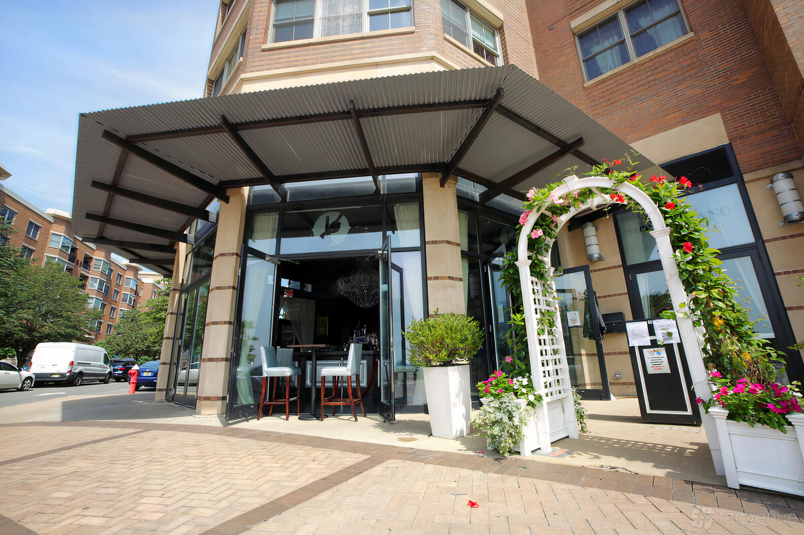A restaurant with glass doors, outdoor seating, and a white floral trellis at Son Cubano.