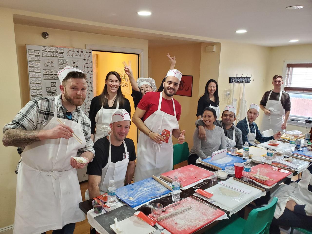 A classroom-style kitchen with guests wearing aprons and chef hats around prep tables at Patty Chen's Dumpling School.