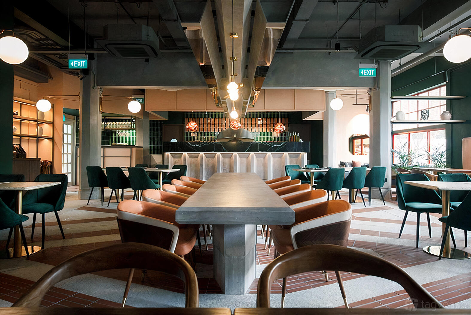 A restaurant with a long communal table, velvet chairs, globe pendant lighting, and an open bar at Tipo Pasta Bar Waterloo.