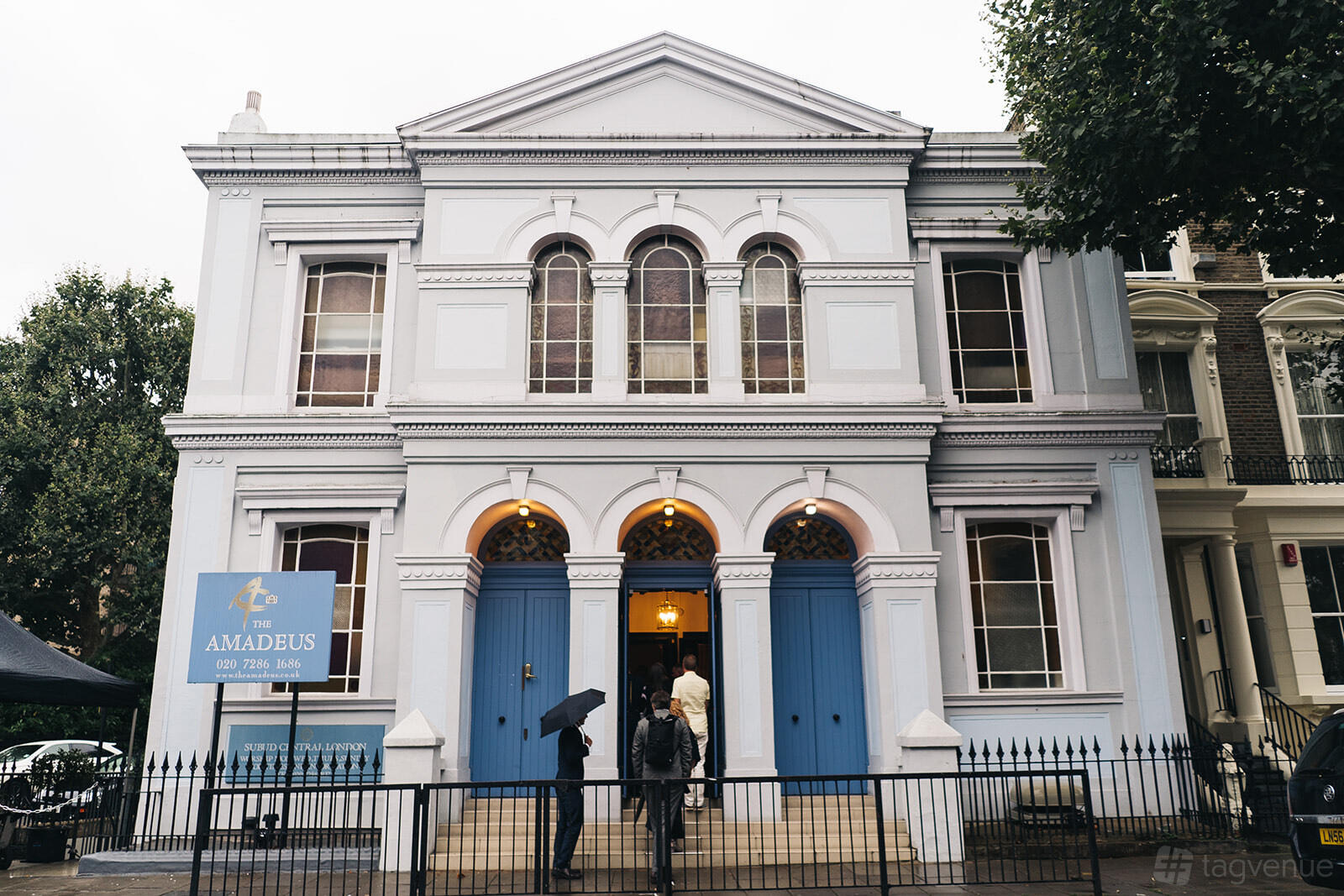 A versatile event space with a neoclassical façade, arched windows, and blue double doors at The Amadeus.