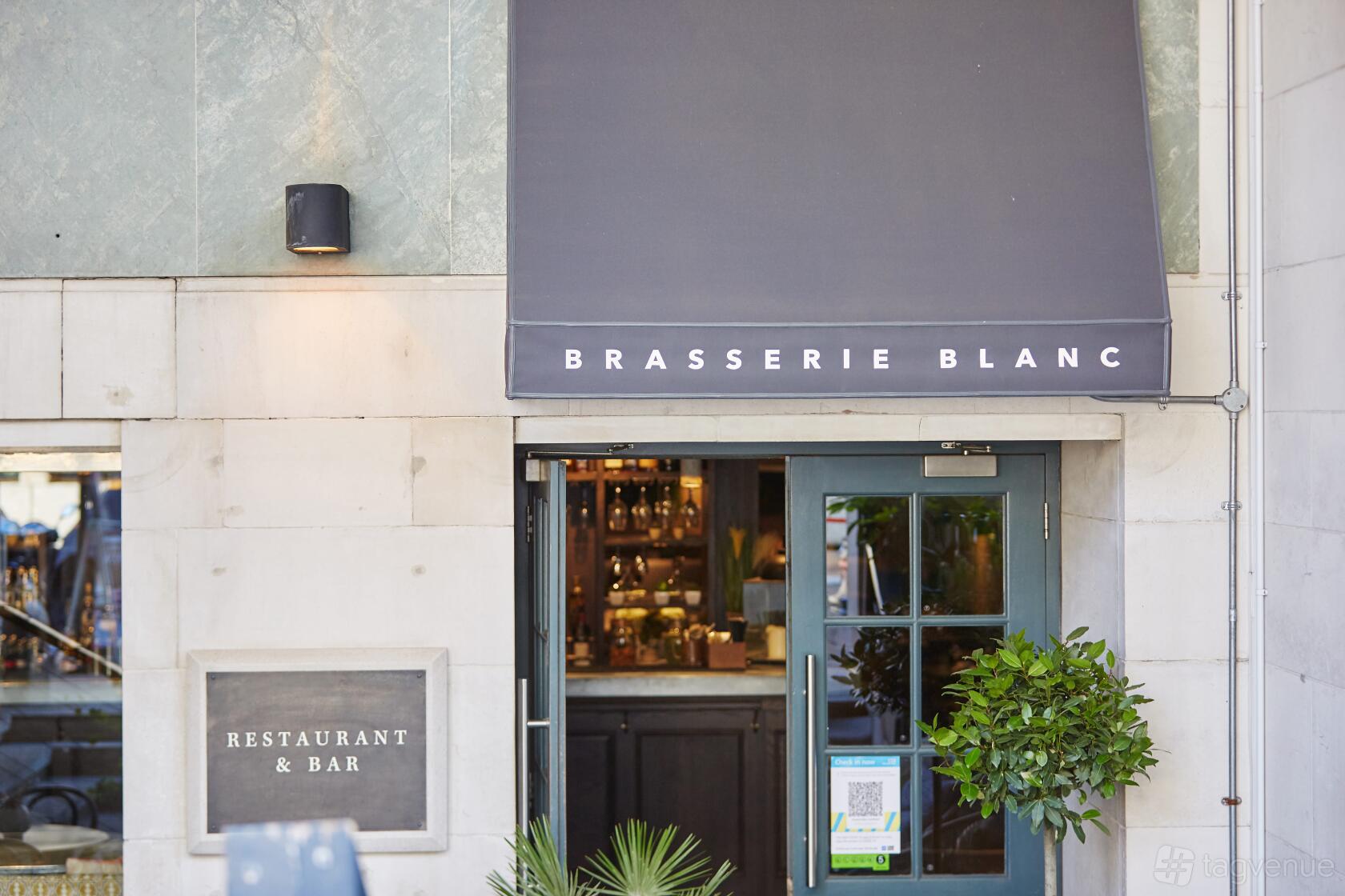 A restaurant entrance with a dark canopy, double doors, and potted greenery at Brasserie Blanc Southbank.