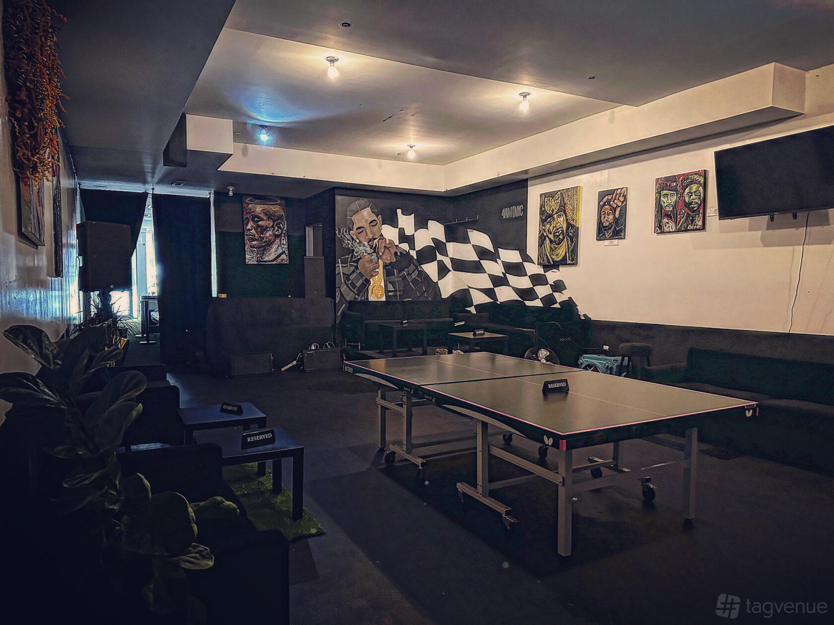 An event venue with a ping pong table, black lounge seating, wall murals, and dim lighting at 4AM NYC.