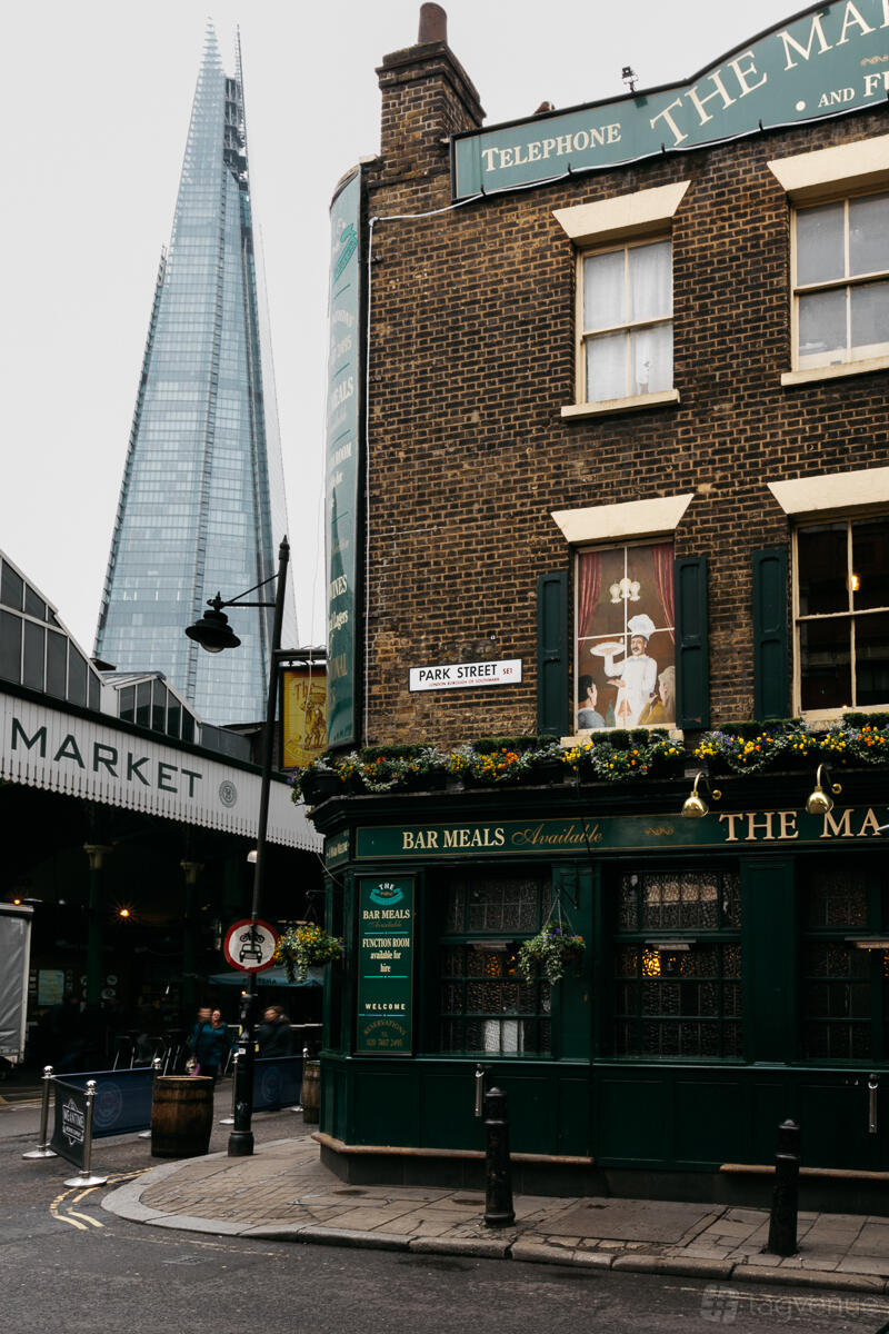 A pub with a brick exterior, painted signage, window flower boxes, and street sign at The Market Porter.