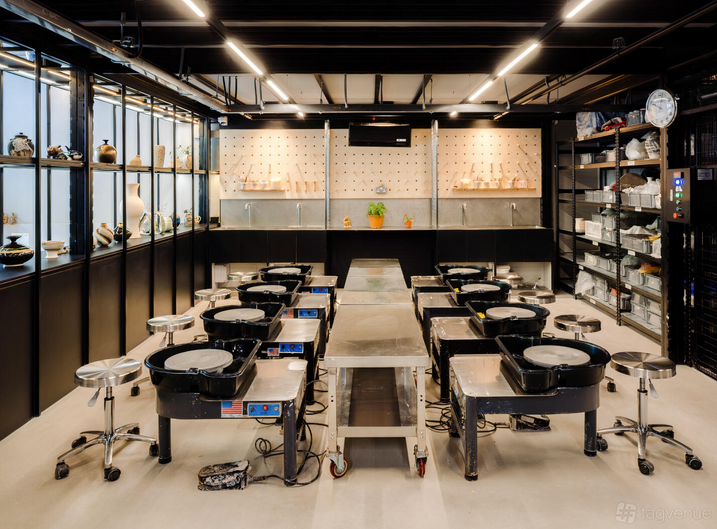 A coworking space with pottery wheels, open shelving, and overhead lighting at Studio GDMC.